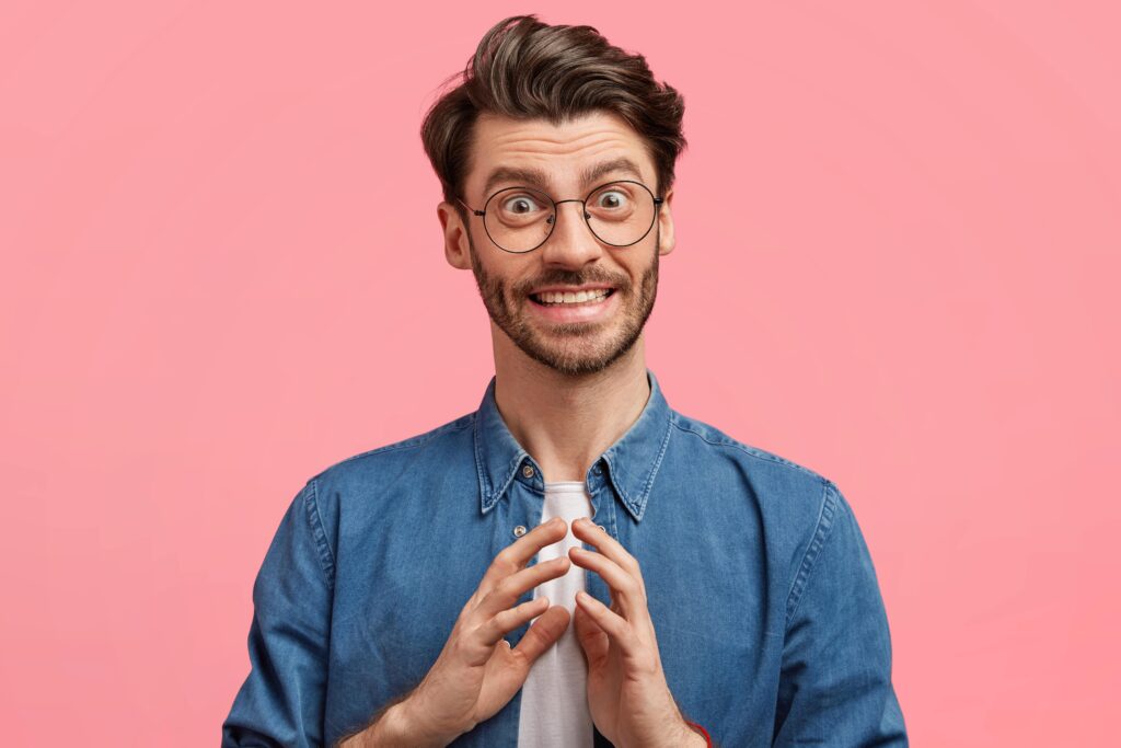 Smiling man with glasses wearing denim shirt against pink background